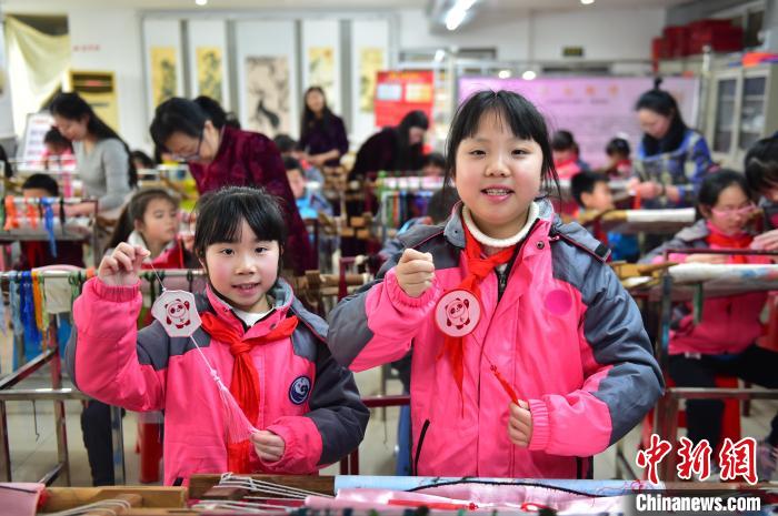 圖為小學生展示繡制好的2022年北京冬奧會吉祥物“冰墩墩”形象?！∮髟屏?攝
