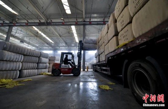 新疆喀什綜合保稅區(qū)，喀什啟路國際貿易有限公司的倉庫內，工人正在裝載從塔吉克斯坦和烏茲別克斯坦進口的棉花。劉新攝