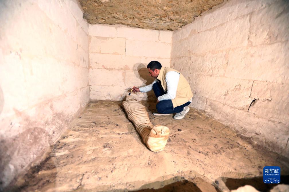 10月15日，在埃及明亞省考古現(xiàn)場(chǎng)，考古人員清理一座石鑿墓中的木乃伊。新華社發(fā)（艾哈邁德·戈馬攝）