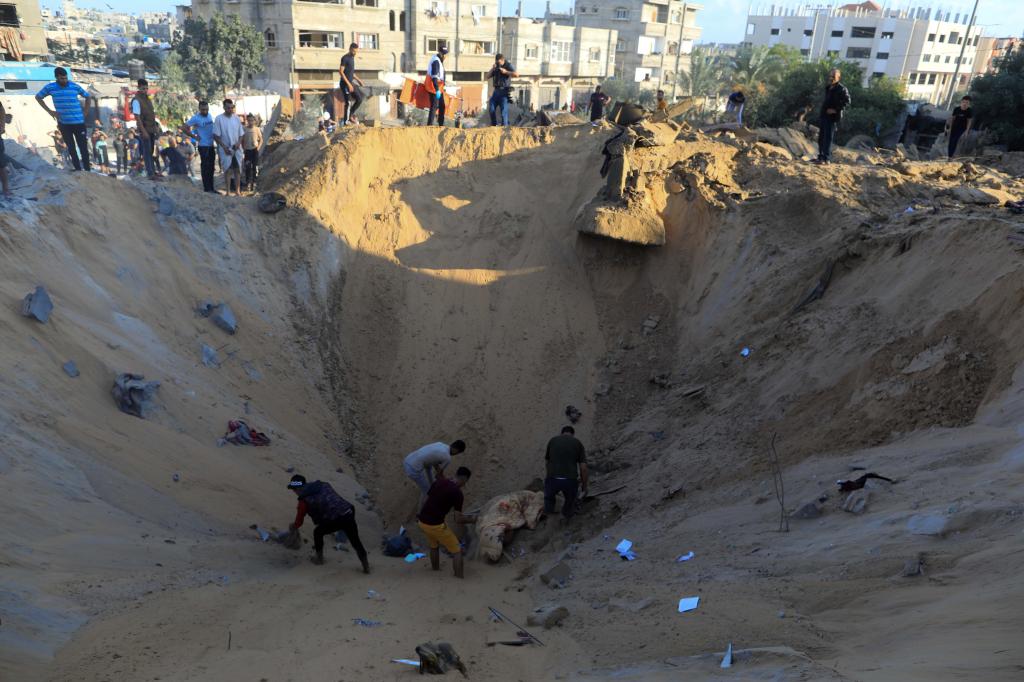 10月16日，在加沙地帶南部城市汗尤尼斯，人們在遭以色列襲擊后的建筑廢墟中救援傷者。 新華社發(fā)（亞西爾·庫迪 攝）