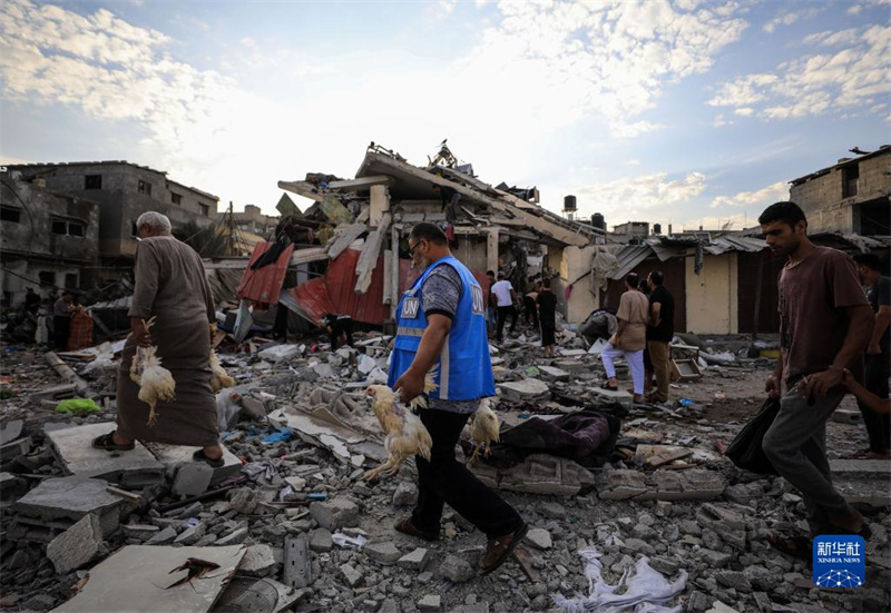 10月27日，在加沙地帶南部城市汗尤尼斯，人們經(jīng)過以軍襲擊后的房屋廢墟。
