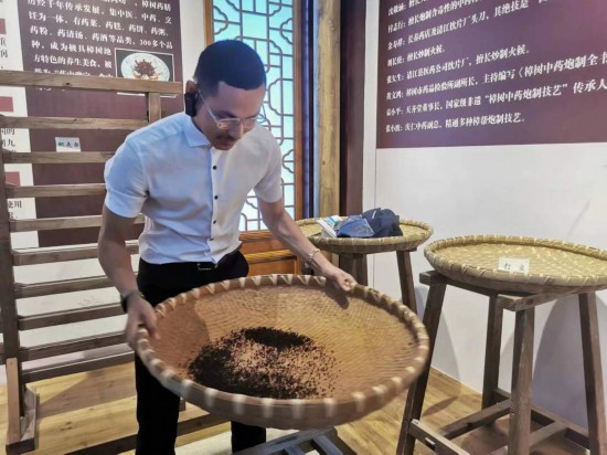 2023“一帶一路”媒體合作論壇聯(lián)合采訪團團員在非遺文化展示館體驗中藥炮制技藝。（本報記者 黃超攝）