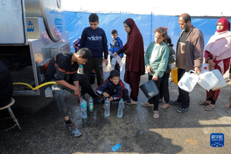 12月8日，在加沙地帶南部城市拉法一處臨時營地內(nèi)，人們排隊打水。新華社發(fā)（里澤克·阿卜杜勒賈瓦德 攝）