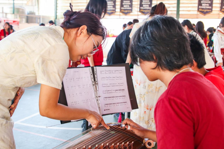 志愿者教師指導學生彈奏古箏。活動主辦方供圖