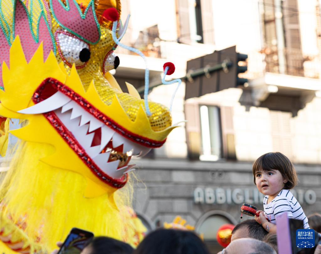 2月18日，在意大利羅馬，一名小朋友在彩妝巡游上觀看舞龍。新華社記者 李京 攝