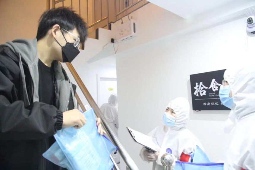 社區(qū)工作人員和志愿者身穿防護(hù)服上門送馬應(yīng)龍大健康防疫包。徐帥攝