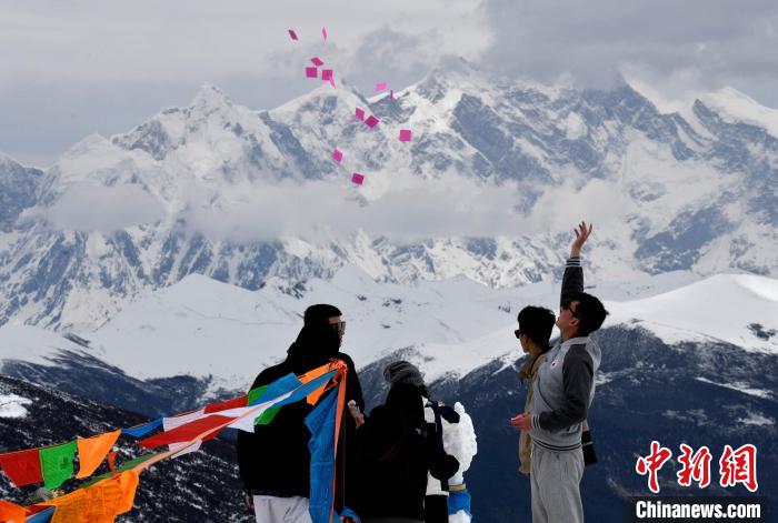 圖為5月14日，游客在西藏林芝色季拉山觀景臺(tái)拋灑“隆達(dá)”(風(fēng)馬旗，藏族民眾的一種祈福方式)?！±盍?攝