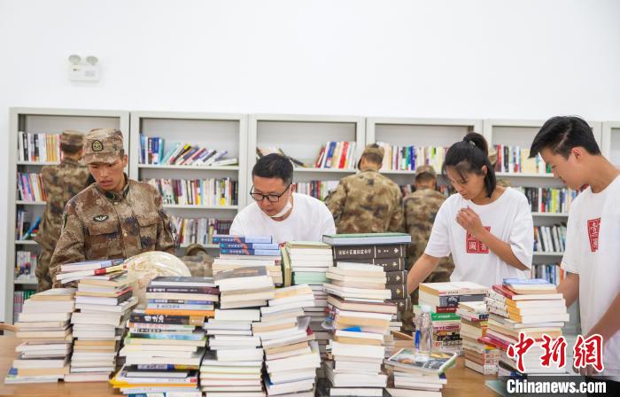 圖為志愿者們和邊防戰(zhàn)士整理圖書(shū)?！詵| 攝