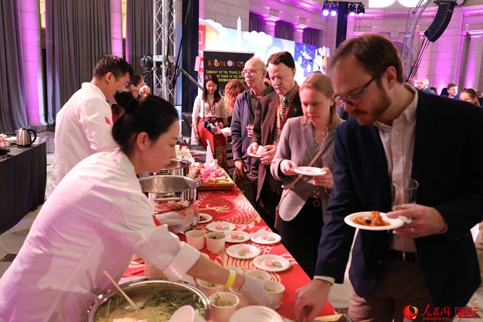 當(dāng)?shù)貢r間3月7日晚，華盛頓聯(lián)合車站廣場舉行駐美使團“使館主廚挑戰(zhàn)賽”。圖為當(dāng)?shù)孛癖娫谥袊古_前體驗中國美食。人民網(wǎng)記者 李志偉攝