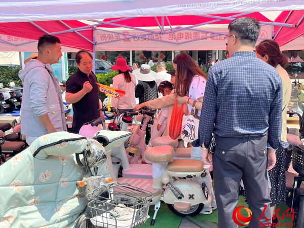 某電動自行車品牌工作人員向消費(fèi)者介紹以舊換新相關(guān)情況。人民網(wǎng)記者 杜燕飛攝