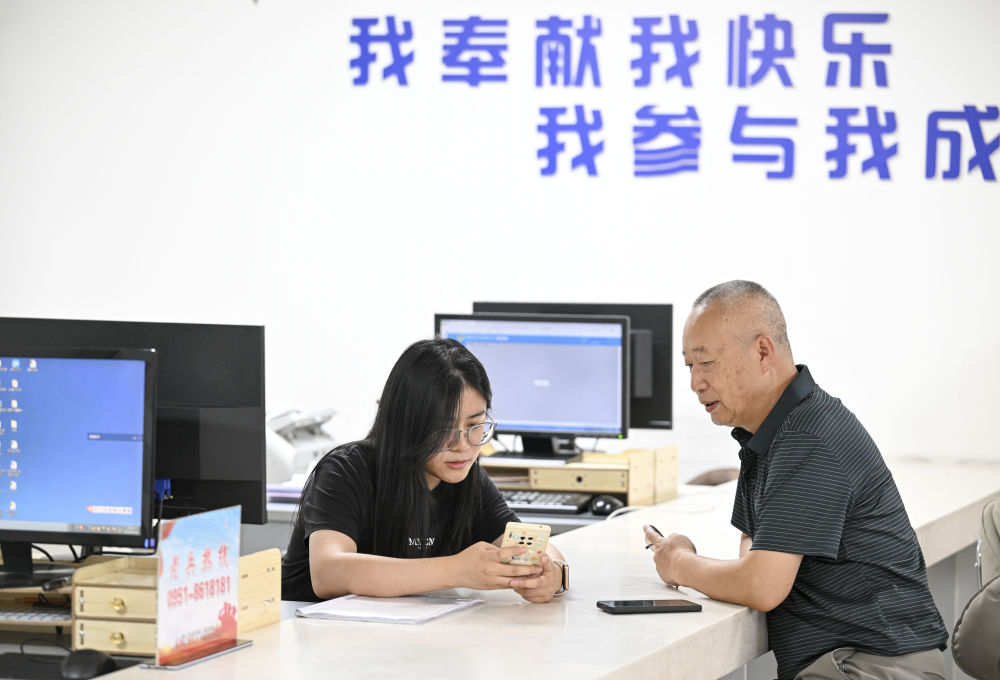 2024年6月20日，在寧夏銀川市金鳳區(qū)長(zhǎng)城花園社區(qū)黨群服務(wù)中心，工作人員幫助居民辦理業(yè)務(wù)。圖片來源 新華社