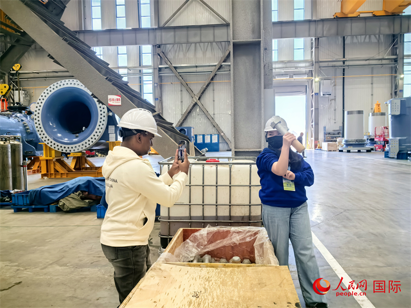 外媒記者掂量廠房內的巨型螺栓。人民網(wǎng) 楊春燕攝