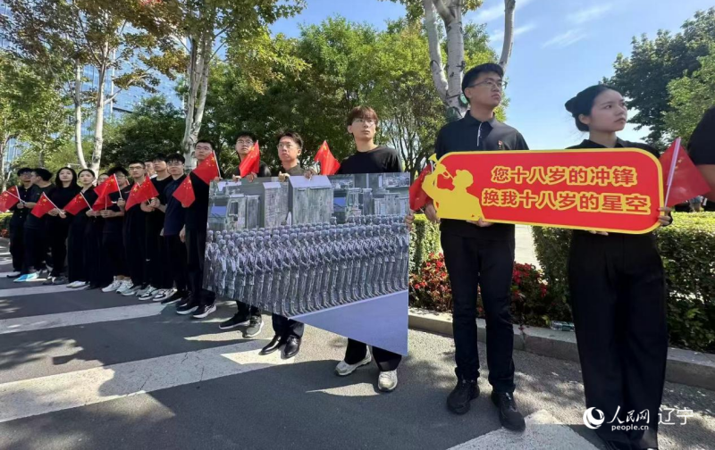 沈陽市人民廣場上，大學(xué)生們手持閱兵的圖片，告慰英烈。人民網(wǎng)記者 周頌雪攝