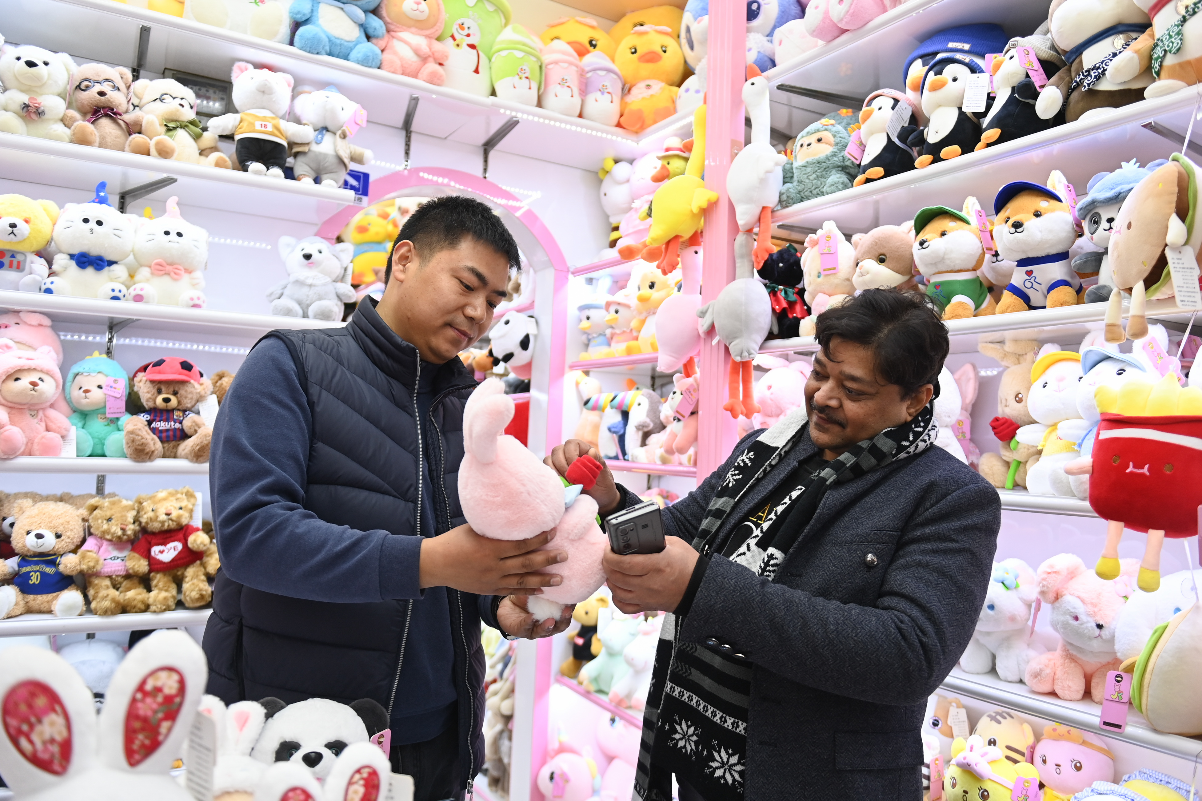 2023年2月2日，來自印度的客商（右）在義烏國(guó)際商貿(mào)城的一家玩具店鋪內(nèi)選購(gòu)。
