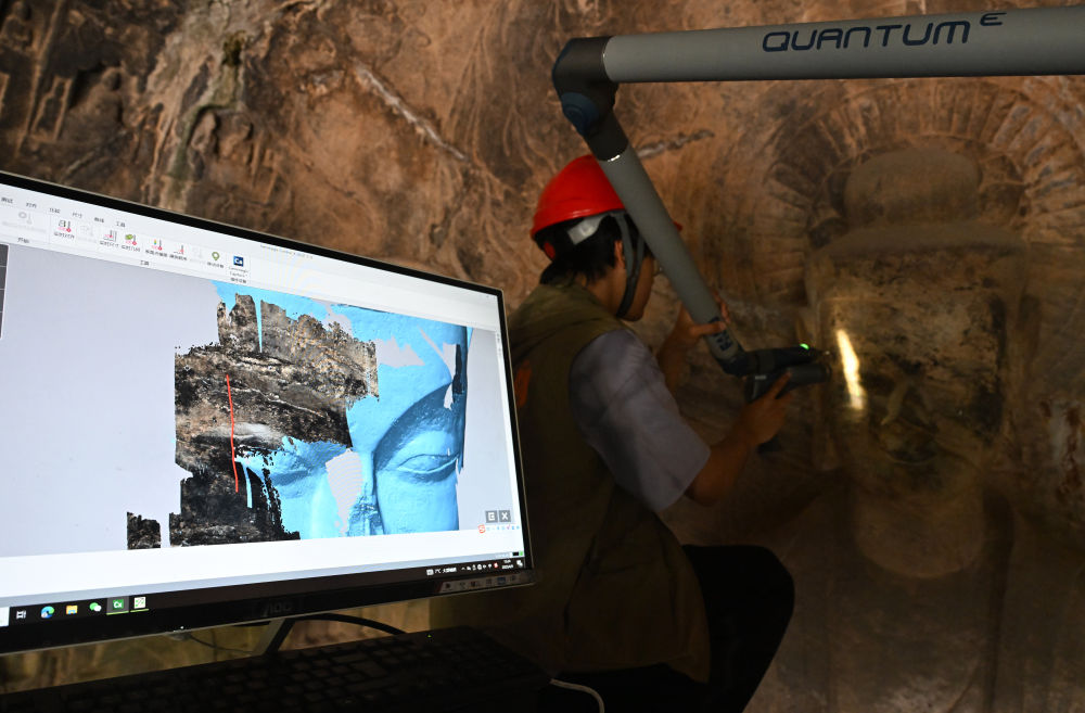 2025年4月9日，武漢大學文化遺產(chǎn)智能計算實驗室團隊成員在魏字洞使用關節(jié)臂掃描儀對佛像進行數(shù)字化掃描。圖片來源新華社