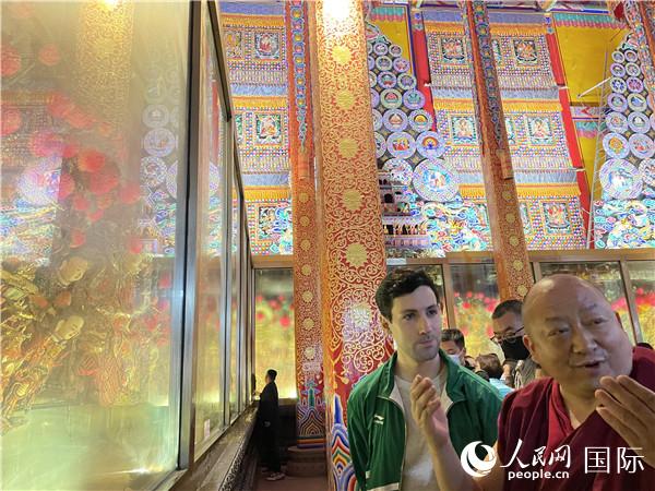 7月25日，省級(jí)非物質(zhì)文化遺產(chǎn)項(xiàng)目塔爾寺酥油花的代表性傳承人朋措堅(jiān)參（右）在塔爾寺酥油花館講解酥油花的制作過(guò)程。人民網(wǎng) 謝瑩攝