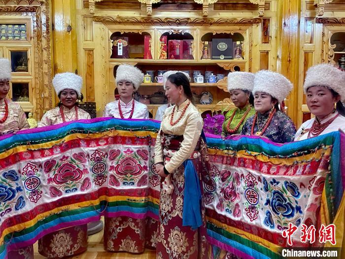 圖為女性展示村民自發(fā)繡制的“百米五彩哈達”?！±钣穹?攝
