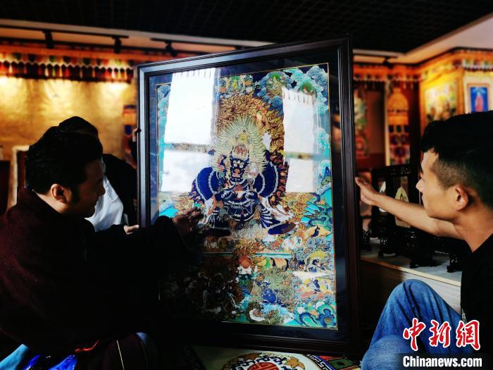 圖為久美尖措(左)與徒弟們展示唐卡作品?！?zhí)砀?攝