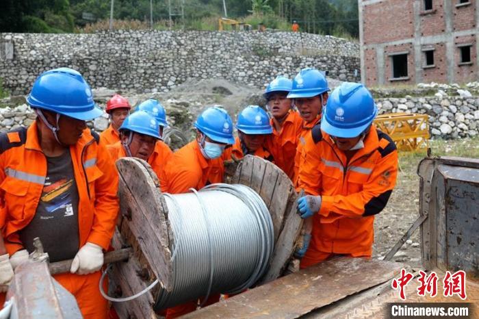國網四川送變電公司搶險隊員將重達370公斤的鋼絞線搬上車?！⑾驸C 攝