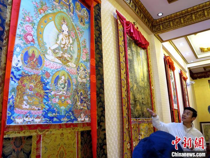 圖為完德尖措展示熱貢龍樹畫苑內(nèi)的唐卡?！?zhí)砀?攝