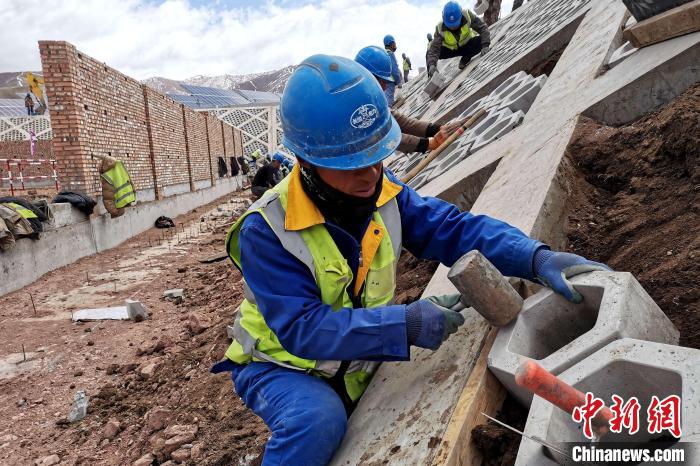 圖為光伏發(fā)電項目施工區(qū)工人在護(hù)坡鋪設(shè)空心磚?！±铍h 攝