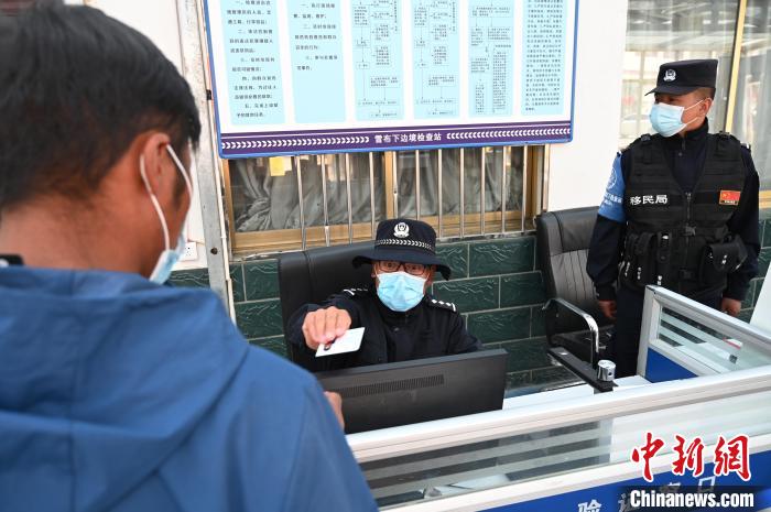 圖為移民管理警察登記完身份信息后將證件歸還給行人?！≮w朗 攝