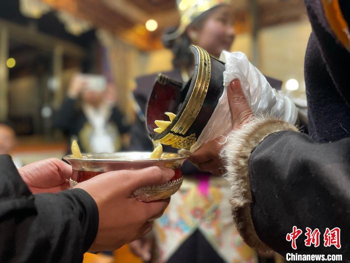 圖為主人在碗中斟滿青稞酒?！∪轿木?攝