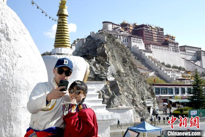 4月17日，游客身著藏式元素服裝在拉薩布達(dá)拉宮觀景臺(tái)拍照留念?！±盍?攝
