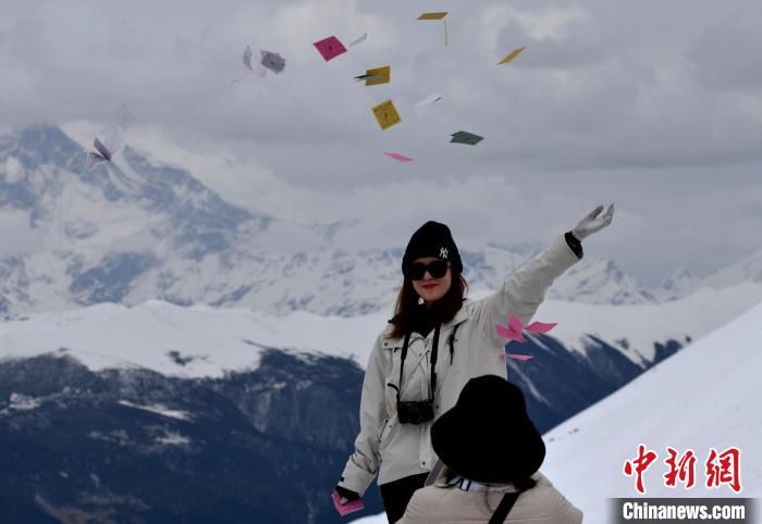 圖為5月14日，游客在西藏林芝色季拉山觀景臺拋灑“隆達”(風馬旗，藏族民眾的一種祈福方式)?！±盍?攝