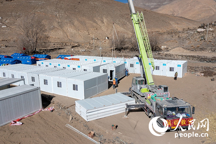 1月9日，在日喀則市定日縣長所鄉(xiāng)古榮村安置點(diǎn)，救援人員和施工人員合力抓緊搭建移動(dòng)板房，確保受災(zāi)群眾溫暖過冬。人民網(wǎng)記者 翁奇羽攝