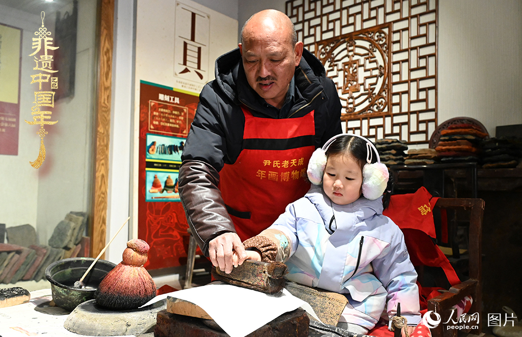 2025年1月27日，河南開封朱仙鎮(zhèn)木版年畫藝人尹國法指導小朋友研習年畫印制技藝。朱仙鎮(zhèn)木版年畫源自漢唐壁畫藝術(shù)，是中國木版年畫的鼻祖。2006年5月20日，朱仙鎮(zhèn)木版年畫經(jīng)國務院批準列入第一批國家級非物質(zhì)文化遺產(chǎn)名錄。人民網(wǎng)記者 王玉興攝